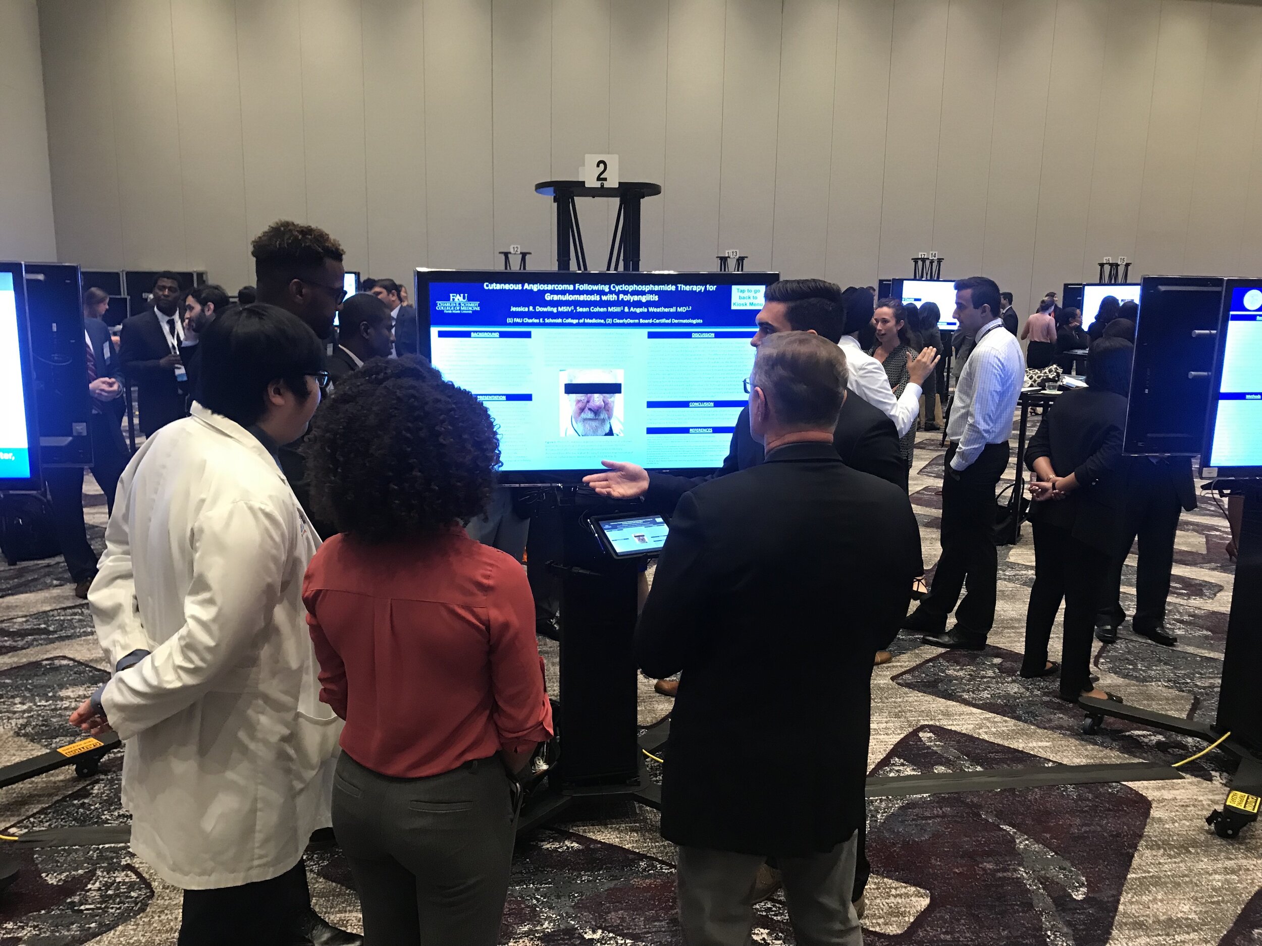 Attendees viewing a digital poster at a conference