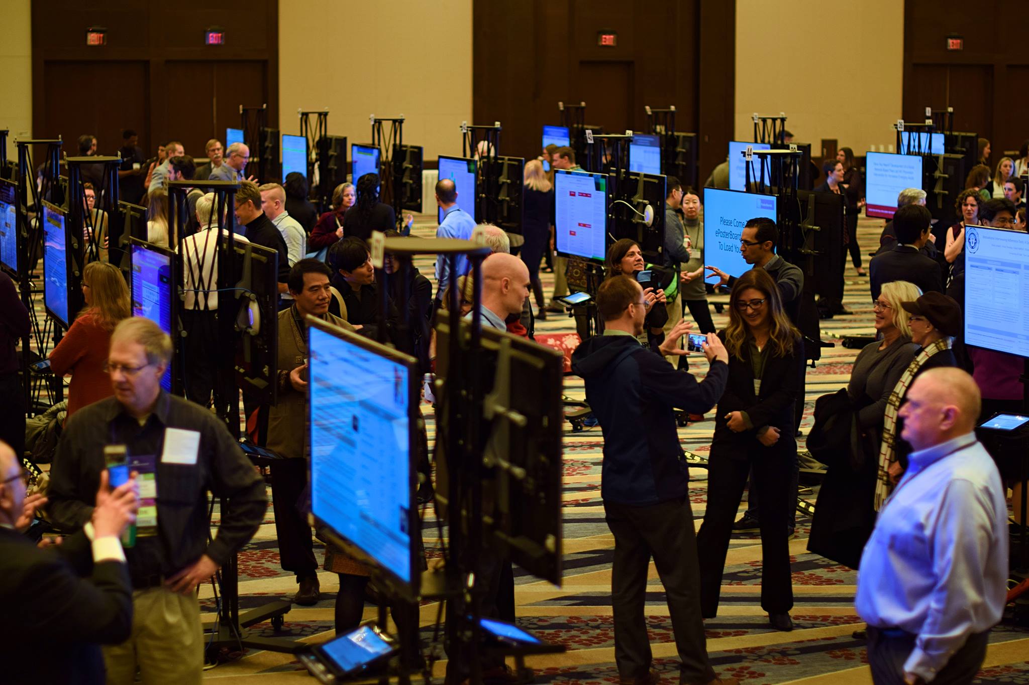 Attendees interacting with digital ePoster displays at a conference