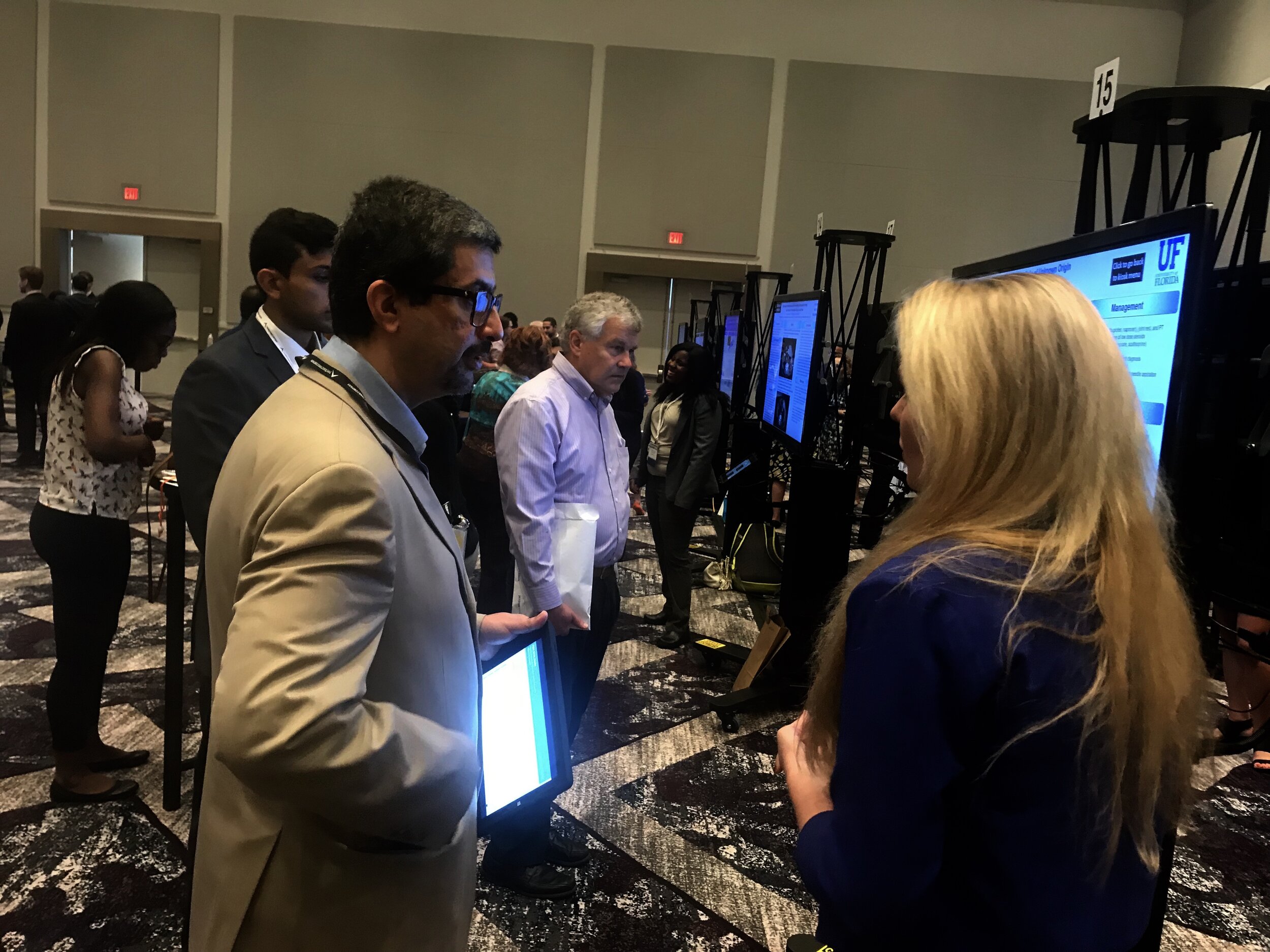 Attendees gathered around digital ePoster displays