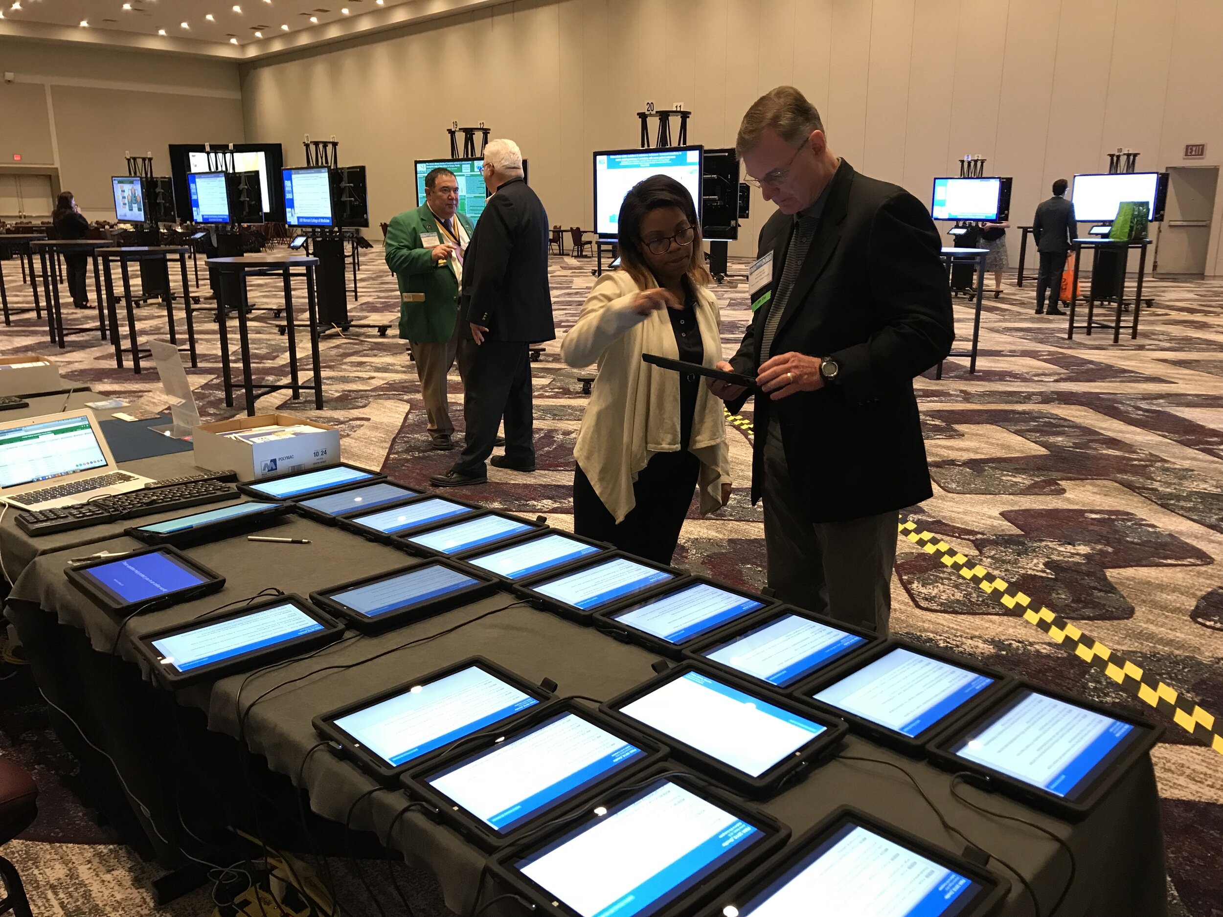 Faculty members reviewing digital posters on tablets