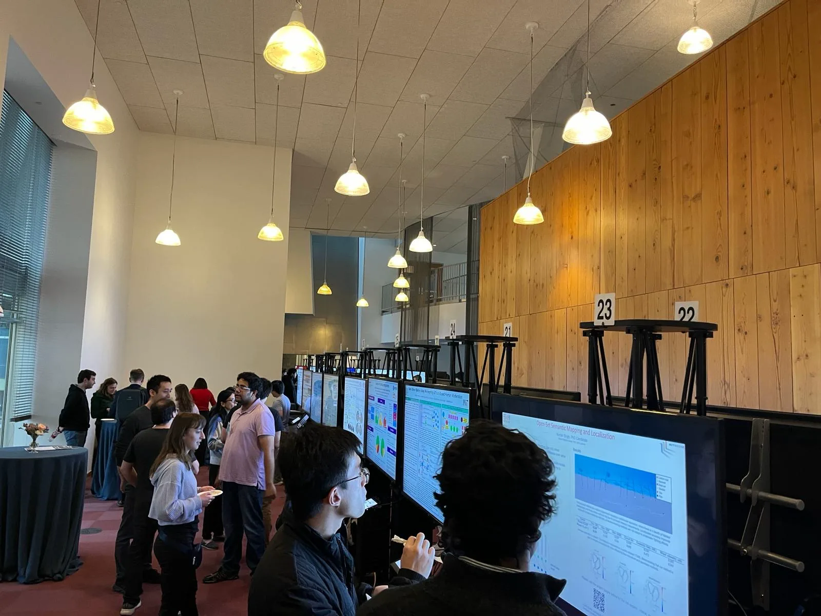 Attendees viewing digital poster displays along a conference wall