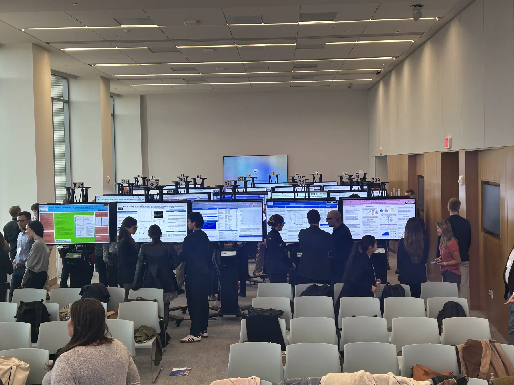 Attendees viewing digital poster boards in a conference room