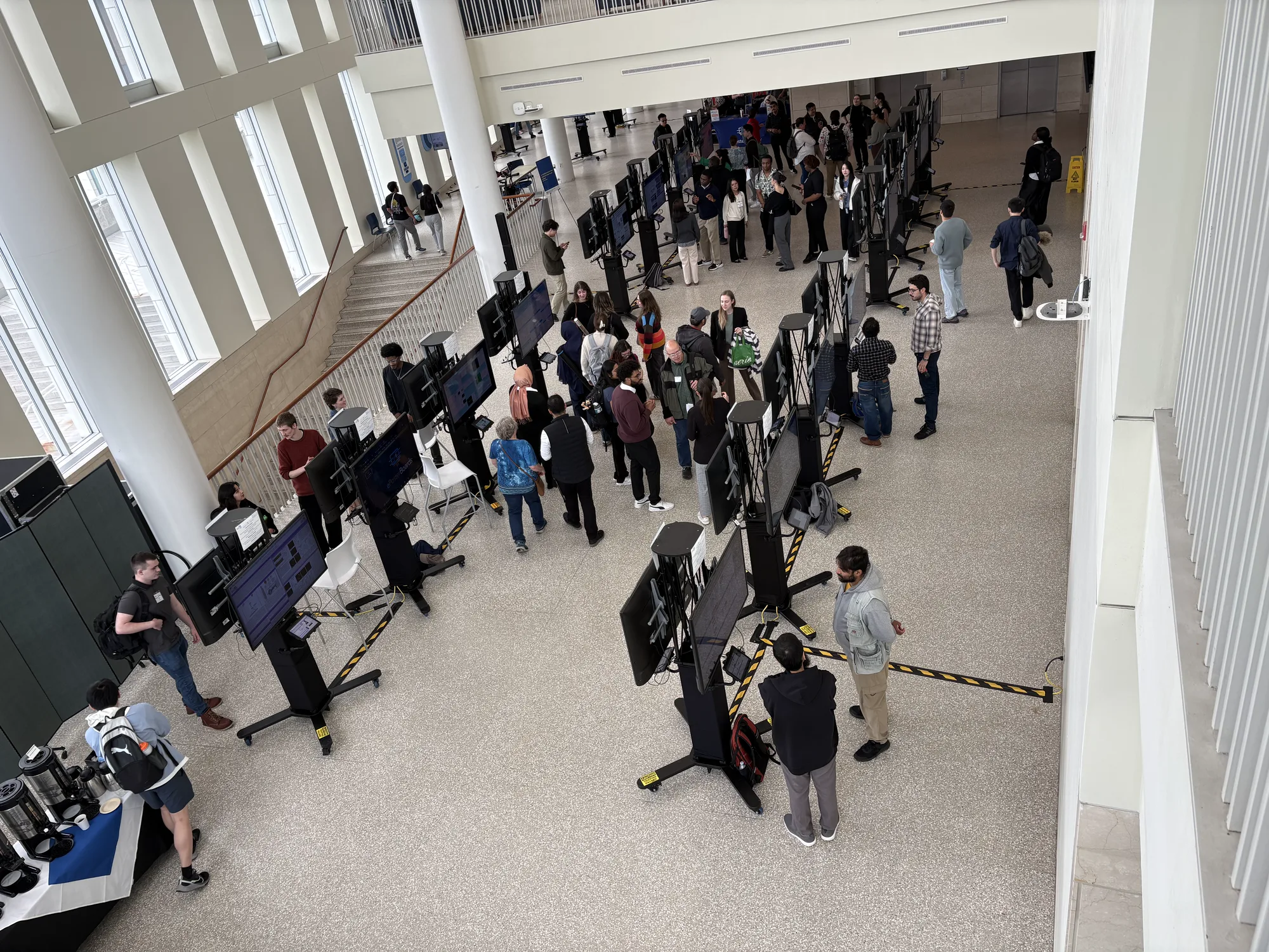 Attendees moving between digital poster displays in a bright conference atrium