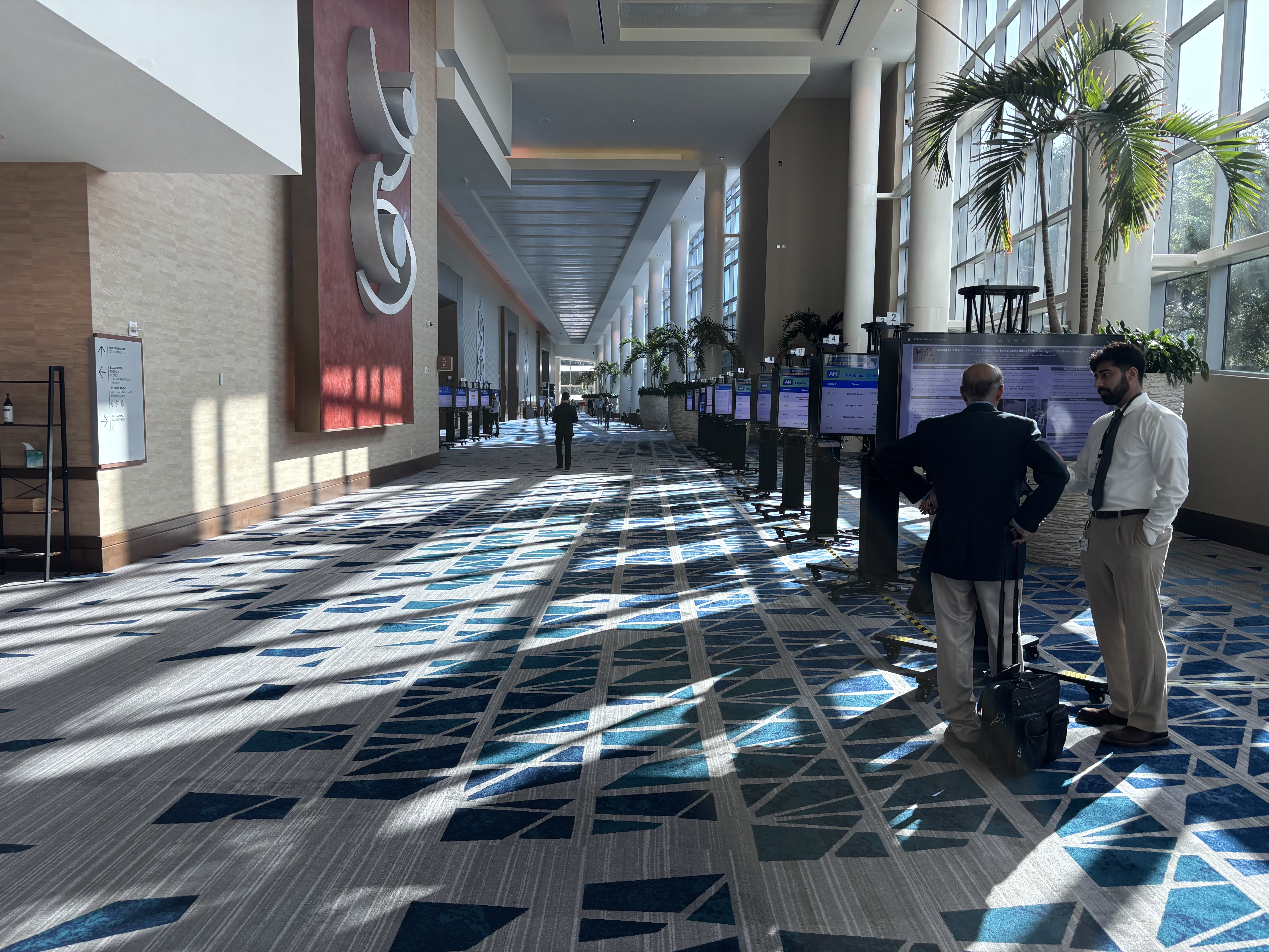 Attendees viewing digital posters in a bright atrium
