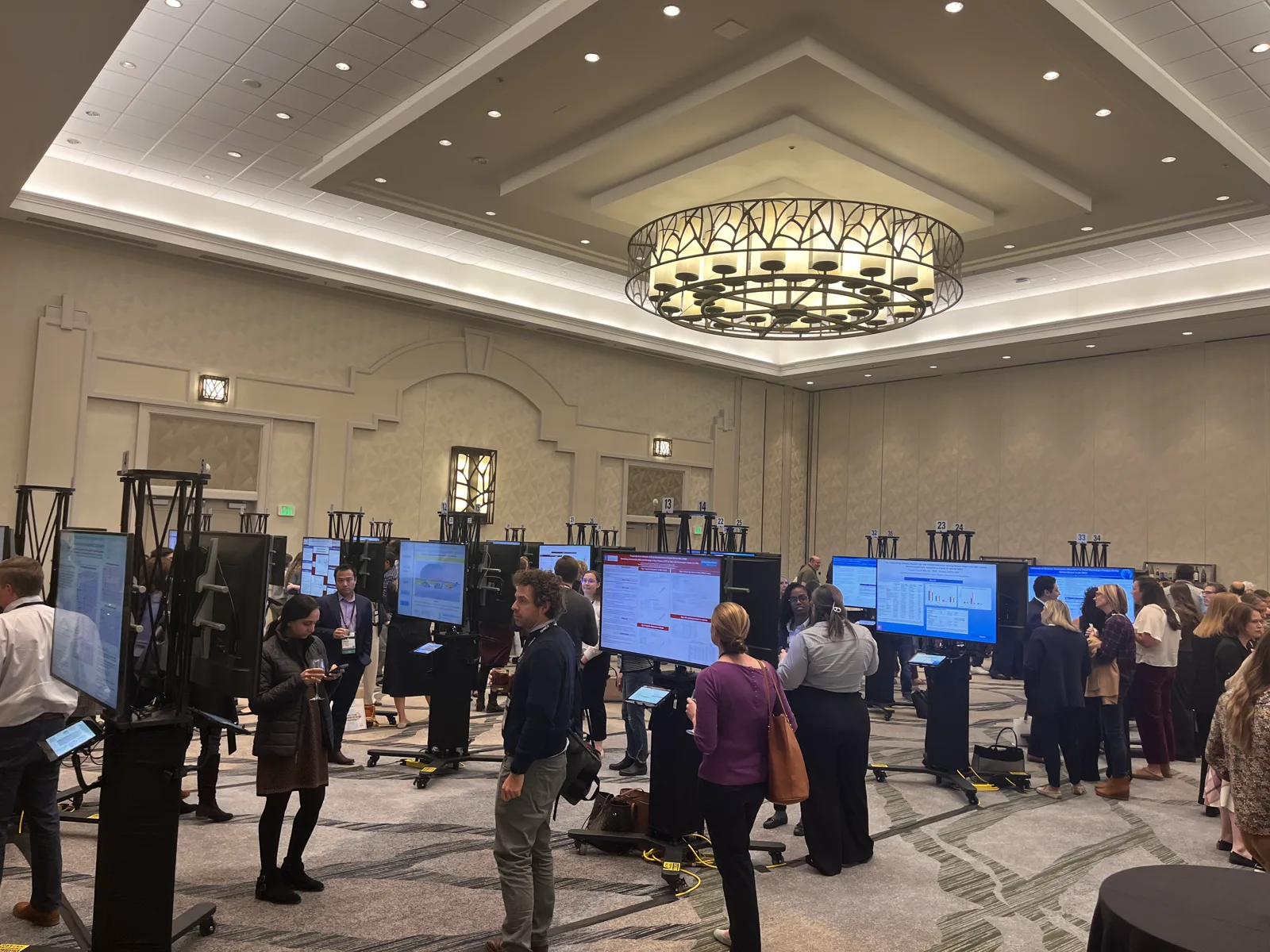 Attendees viewing digital ePoster boards in a conference hall